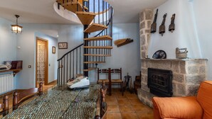 Un escalier en colimaçon, une cheminée et un coin repas avec une table et des chaises.