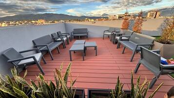 A rooftop patio with seating and planters.
