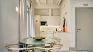 A compact kitchen with a microwave, a small dining table with chairs, and a door with a sign. - Luis de Vargas 1A by Home at Homes (Seville)