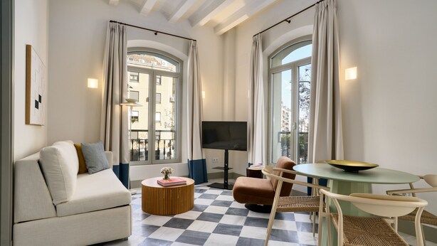 A modern living room with a sofa, chairs, a round table, and a TV. - Luis de Vargas 1A by Home at Homes (Seville)