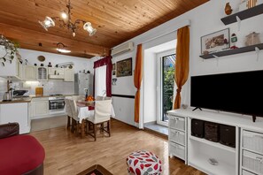 A modern kitchen with white cabinets, a dining table, and a TV on a white stand. - Apartments Kata - Three Bedroom Apartment With Balcony (Makarska)