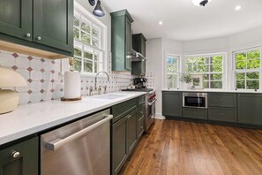A kitchen with dark green cabinets, a stainless steel dishwasher, a built-in oven, and a large window. - Holly House-1mi to UofA-0.5mi to RazorbackGreenway (Fayetteville)