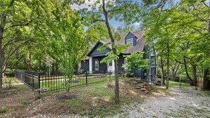 A house with a gravel driveway, surrounded by trees and a black metal fence. - Holly House-1mi to UofA-0.5mi to RazorbackGreenway (Fayetteville)