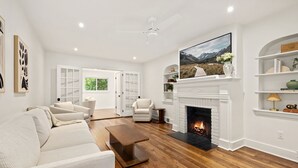 A modern living room with a fireplace, white walls, and wooden flooring. - Holly House-1mi to UofA-0.5mi to RazorbackGreenway (Fayetteville)