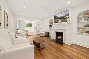 A modern living room with a fireplace, white walls, and wooden flooring. - Holly House-1mi to UofA-0.5mi to RazorbackGreenway (Fayetteville)