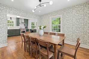 A modern kitchen with green cabinets, a wooden dining table, and a large window. - Holly House-1mi to UofA-0.5mi to RazorbackGreenway (Fayetteville)