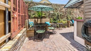 A patio area with a table and chairs, a wooden bench, and a brick wall. - French Quarter Jazz Hideaway and Courtyard (New Orleans)