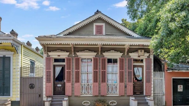 A two-story house with a front porch, a small garden, and a gate. - French Quarter Jazz Hideaway and Courtyard (New Orleans)