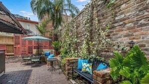 A courtyard with a brick wall, outdoor furniture, and plants. - French Quarter Jazz Hideaway and Courtyard (New Orleans)