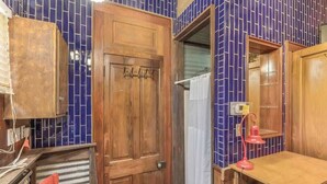 A bathroom with a wooden door, a red chair, a sink, and a mirror. - French Quarter Quirky and Cozy Private Bunk Room (New Orleans)
