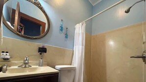 Ein Badezimmer mit Toilette, Waschbecken, Spiegel und Duschvorhang.