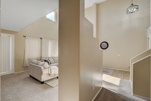 Ein Schlafzimmer mit Bett, Fenster, Treppe und einer Uhr an der Wand.