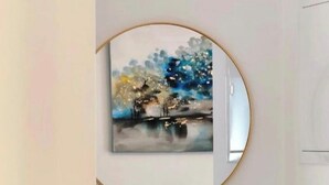 Ein an der Wand befestigter runder Spiegel mit einem Bild, ein kleines Regal mit einem Kalender und einem Schilferdiffusor.