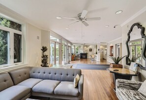 A spacious living area with a large gray sofa, a wooden coffee table, and a ceiling fan. - Elliott Bay View Condo Near Everything and Seattle Center with AC and More! (Seattle)