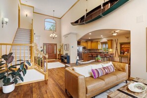 A spacious living area with a staircase, a kitchen, and a dining area. - Lakefront Retreat on Okauchee | Theater, Hot Tub, Bunk Room + 50’ Frontage (Oconomowoc)