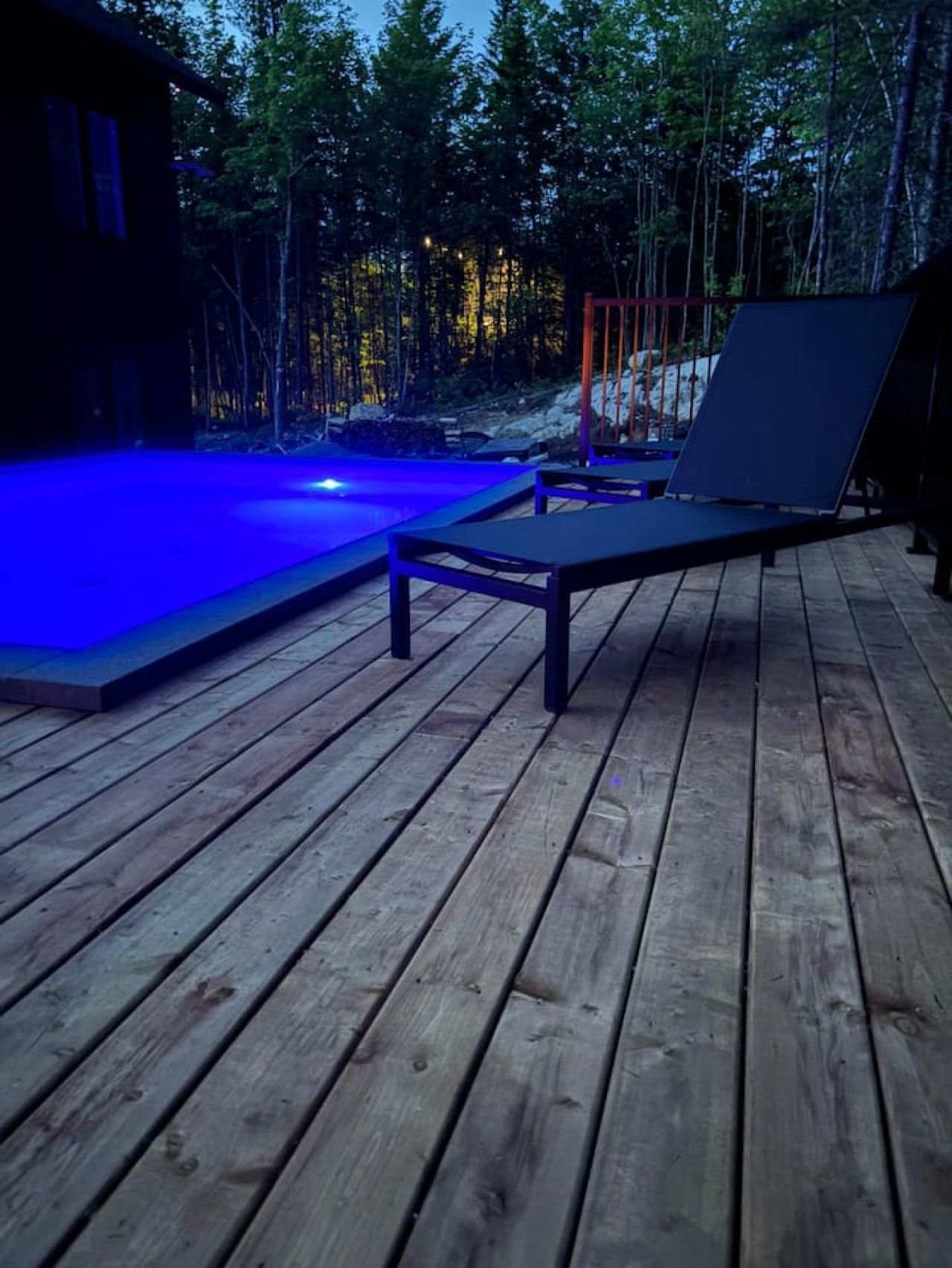 A wooden deck with a pool and lounge chairs.