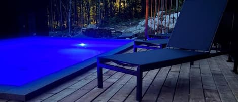 Eine Holzterrasse mit Pool und Liegestühlen.