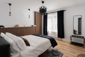 Ein modernes Schlafzimmer mit einem Bett, einem Nachttisch und einem großen Fenster mit Vorhängen.