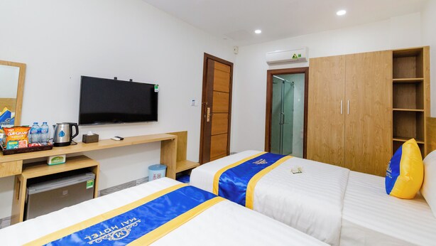 A hotel room with two beds, a TV, a minibar, and a wooden wardrobe. - Mai Hotel Airport (Ho Chi Minh City)