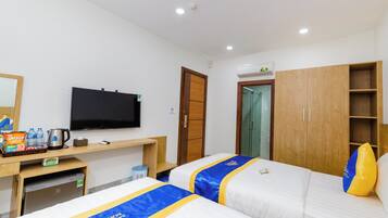 Una habitación de hotel con dos camas, televisión, minibar y armario de madera.