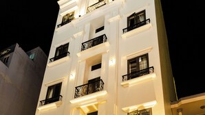 A hotel with a prominent sign, multiple balconies, and a staircase leading to the entrance. - Mai Hotel Airport (Ho Chi Minh City)