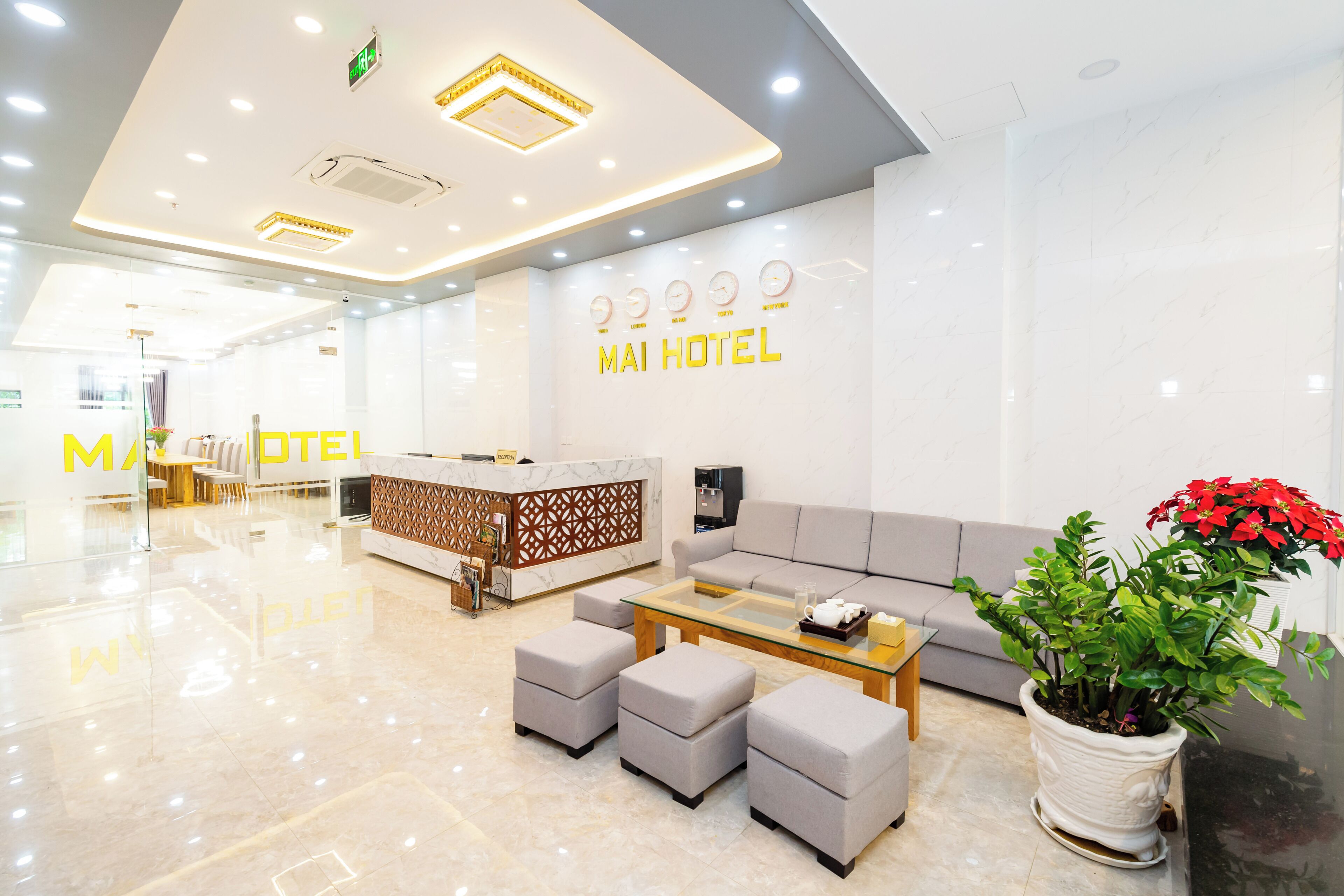 Zona de recepción de un hotel con diseño moderno, que incluye un mostrador de recepción, un área de descanso y una planta en maceta.