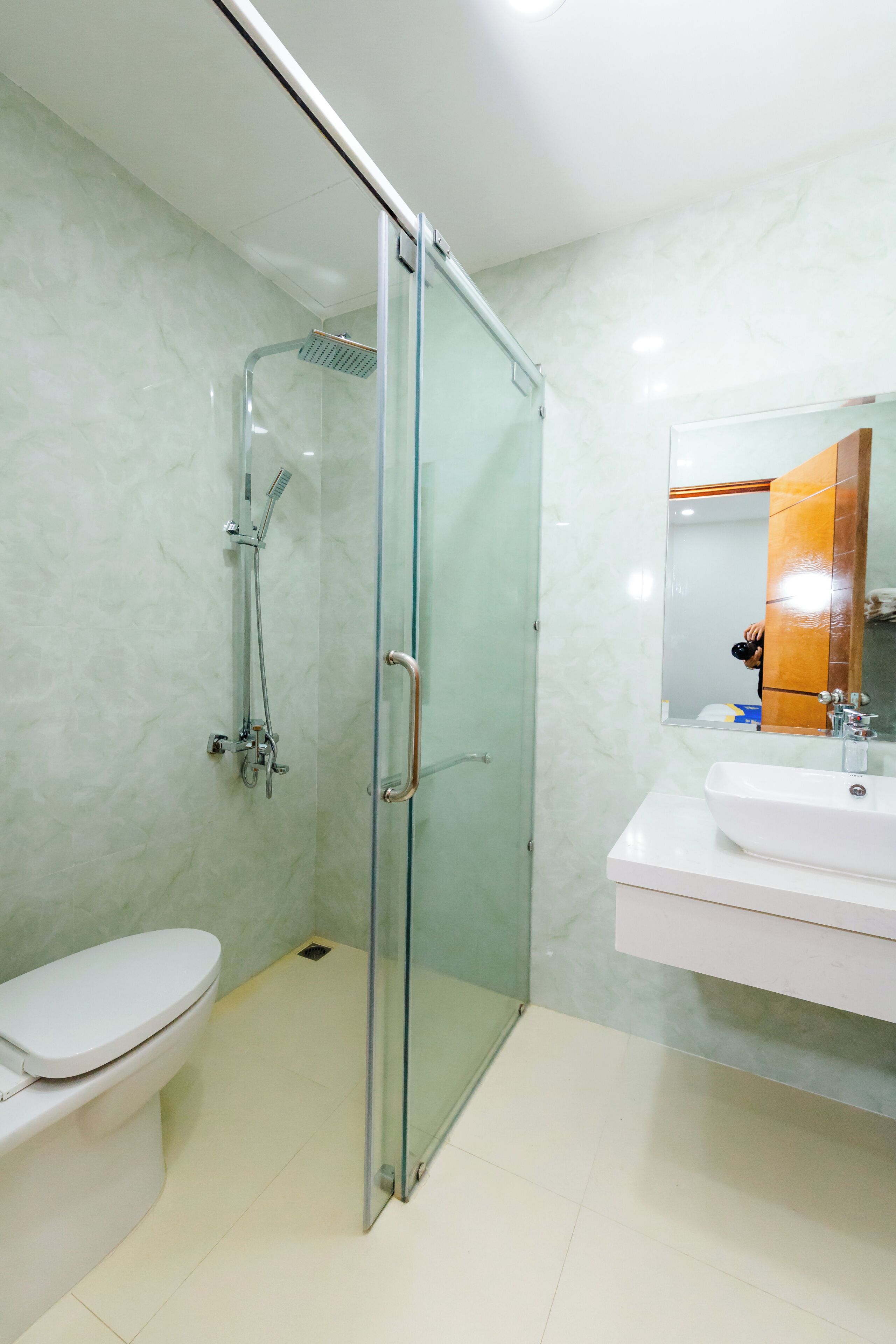 A bathroom with a glass-enclosed shower, a white toilet, and a sink with a mirror.