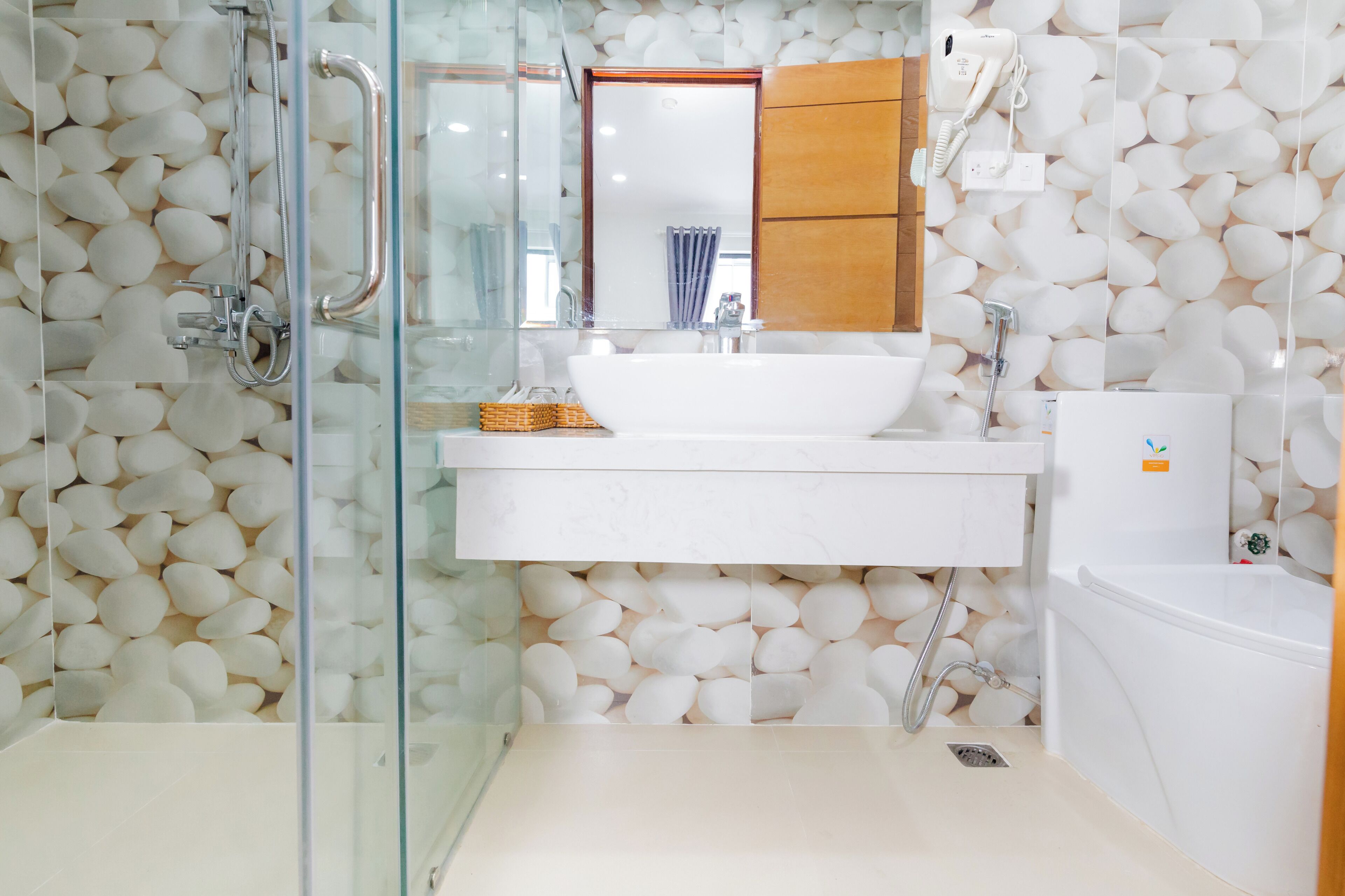 Un baño con cabina de ducha de vidrio, lavamanos blanco y bañera.