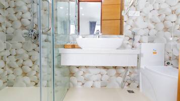 Un baño con cabina de ducha de vidrio, lavamanos blanco y bañera.
