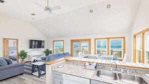 Una cocina moderna con lavavajillas, un comedor con mesa y sillas, un sofá y una televisión.