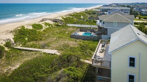 Zona residencial costera con piscina, acceso a la playa y casas con balcones.