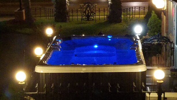 A hot tub with surrounding lights, a fence, and potted plants. - Spacious hotel efficiencies walking distance to all Saratoga has to offer (Saratoga Springs)
