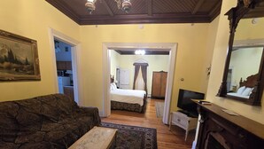 A room with a sofa, a television, a fireplace, and a bed with a canopy. - Spacious hotel efficiencies walking distance to all Saratoga has to offer (Saratoga Springs)