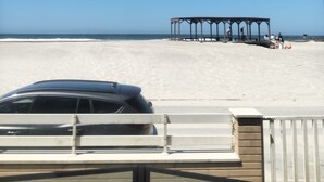 Vista da praia com um pavilhão e um carro em primeiro plano.