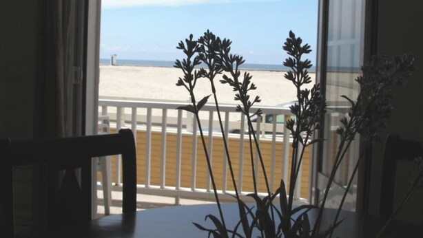 Quarto com vista para a praia, corrimão branco e uma mesa com cadeiras.