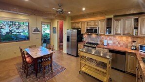 A kitchen with wooden cabinets, a stainless steel refrigerator, a microwave, and a gas stove. - Raven's Haven in the Heart of Santa Fe (Santa Fe)