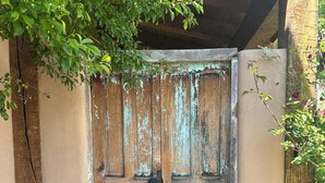 A rustic wooden door with a metal latch, set in a weathered wall with peeling paint. - Raven's Haven in the Heart of Santa Fe (Santa Fe)