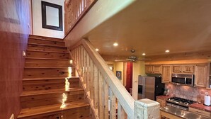 Una scala in legno conduce a una zona cucina con forno a microonde e piano cottura.
