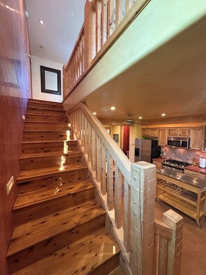 A wooden staircase leading to a kitchen area with a microwave and stove. - Raven's Haven in the Heart of Santa Fe (Santa Fe)