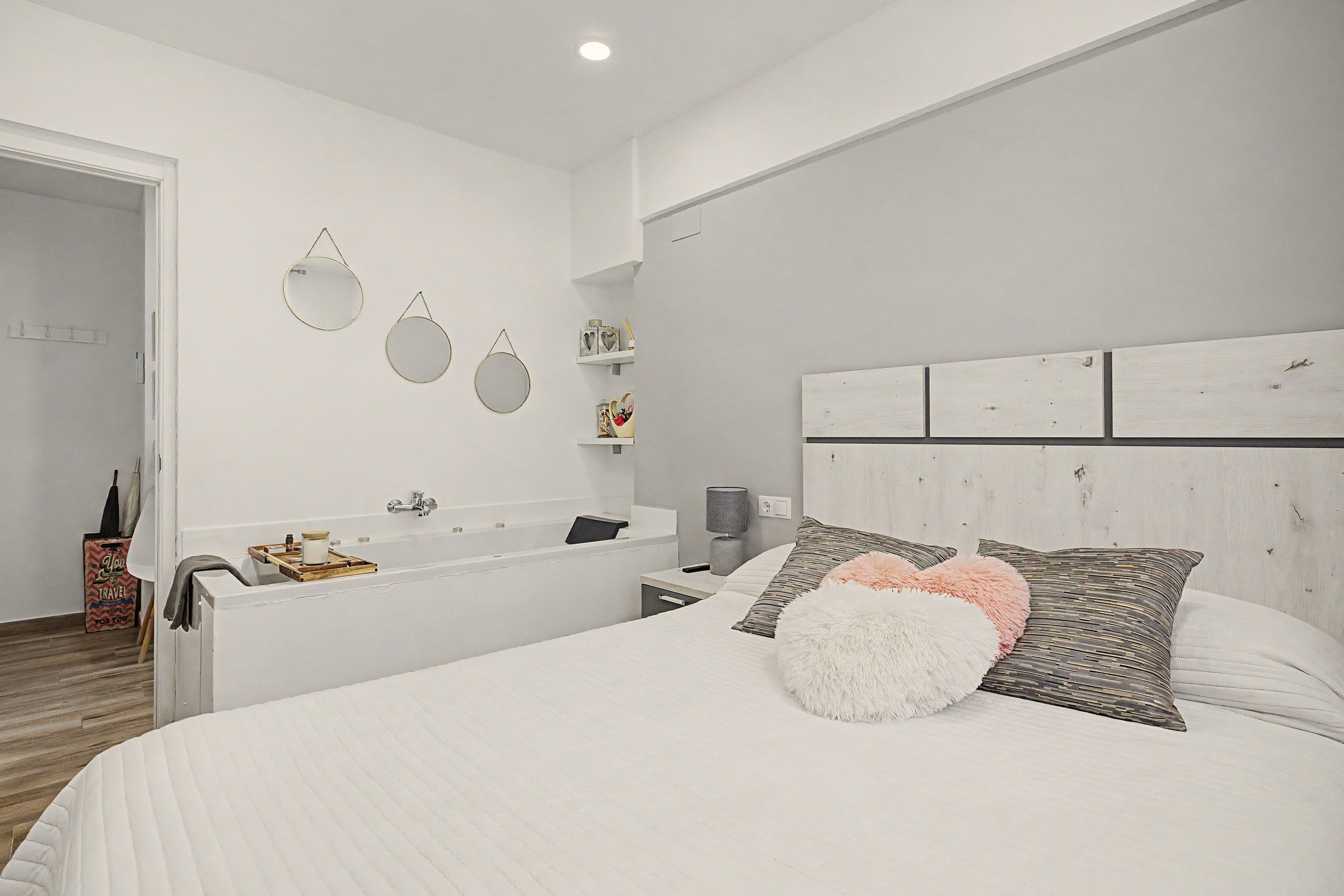 Une chambre à coucher moderne avec un grand lit, une baignoire intégrée et une décoration aux tons blancs.