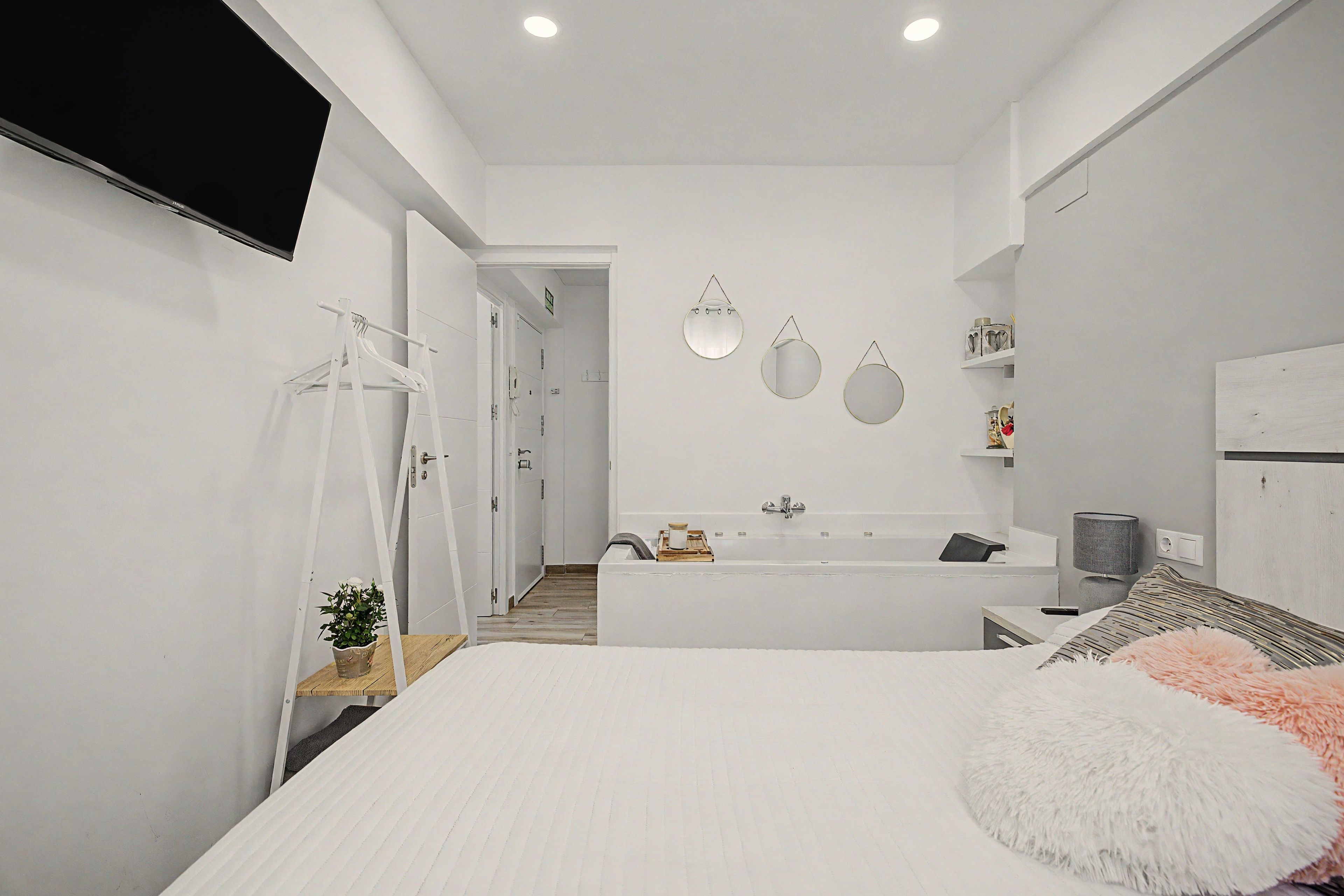 A modern bathroom with a bathtub, a shower, and a toilet. There are two mirrors on the wall, and a towel rack is visible.