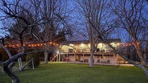 A two-story house with a covered patio, outdoor seating, and string lights. - Ingrid’s Green Haven - 27 Acre Private Farm (Wiarton)