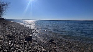 A rocky shoreline with clear water and a bright sun in the sky. - Ingrid’s Green Haven - 27 Acre Private Farm (Wiarton)