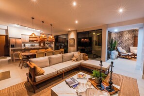 A modern living room with a sofa, coffee table, and dining area. - Luxury Villa In Los Cobanos Sonsonate (Acajutla)