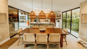 Een moderne keuken met een centraal eiland, hanglampen en uitzicht op de omgeving.