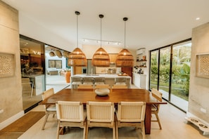 Een moderne keuken met een centraal eiland, hanglampen en uitzicht op de omgeving.