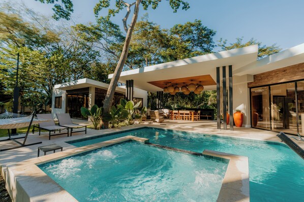 A modern outdoor pool area with lounge chairs, a barbecue, and a covered seating area. - Luxury Villa In Los Cobanos Sonsonate (Acajutla)
