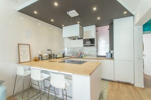 Une cuisine moderne dotée d’un îlot central, de tabourets de bar, d’un four à micro-ondes et d’un réfrigérateur.