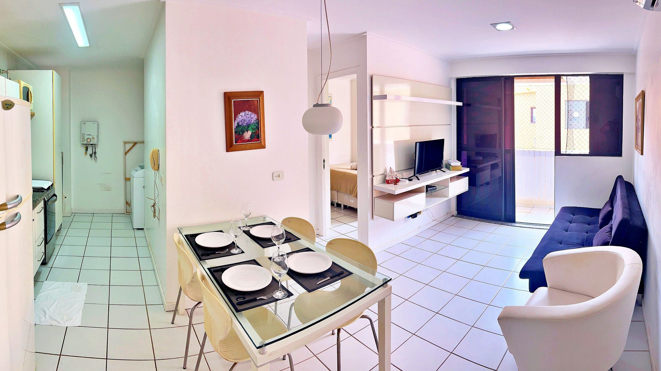 A compact living space with a dining area, a sofa, a TV, and a kitchenette.