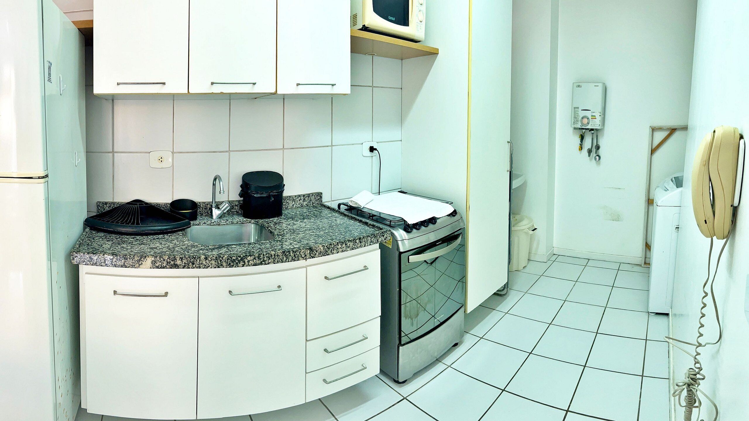 Una cocina con armarios blancos, encimera de granito, estufa y microondas.